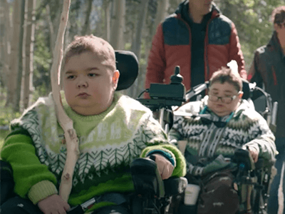 barn med neuromuskulär sjukdom i naturen med rullstol