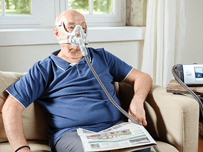 copd patient ventilationsmaskin lumis läser en tidning med PAP mask